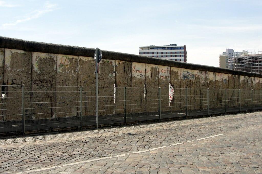 Imagem do Muro de Berlim durante o dia do lado esquerdo da imagem.